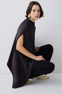 Person wearing a brown outfit with a cape on a white background