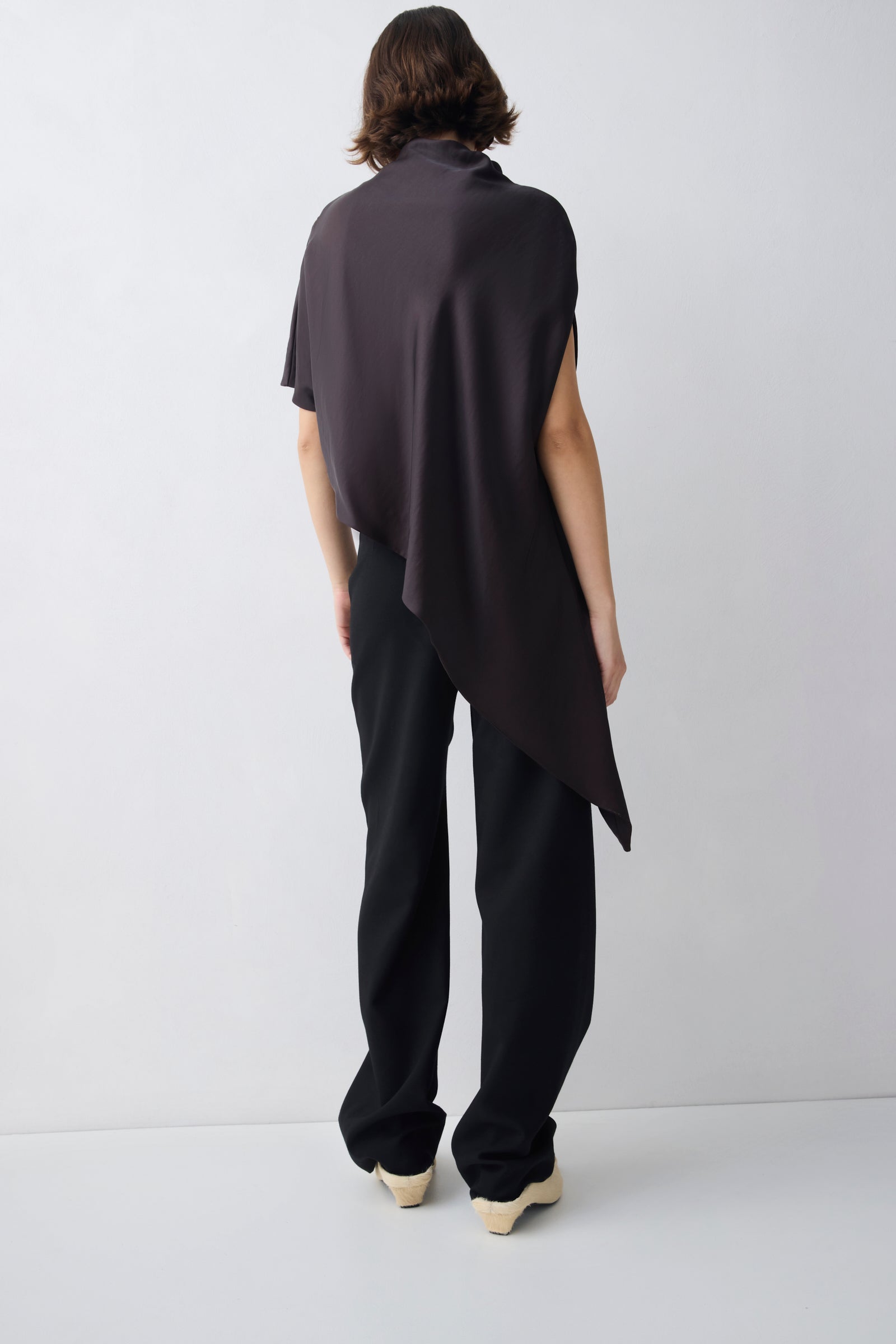 Person wearing a brown sleeveless top and pants on a white background