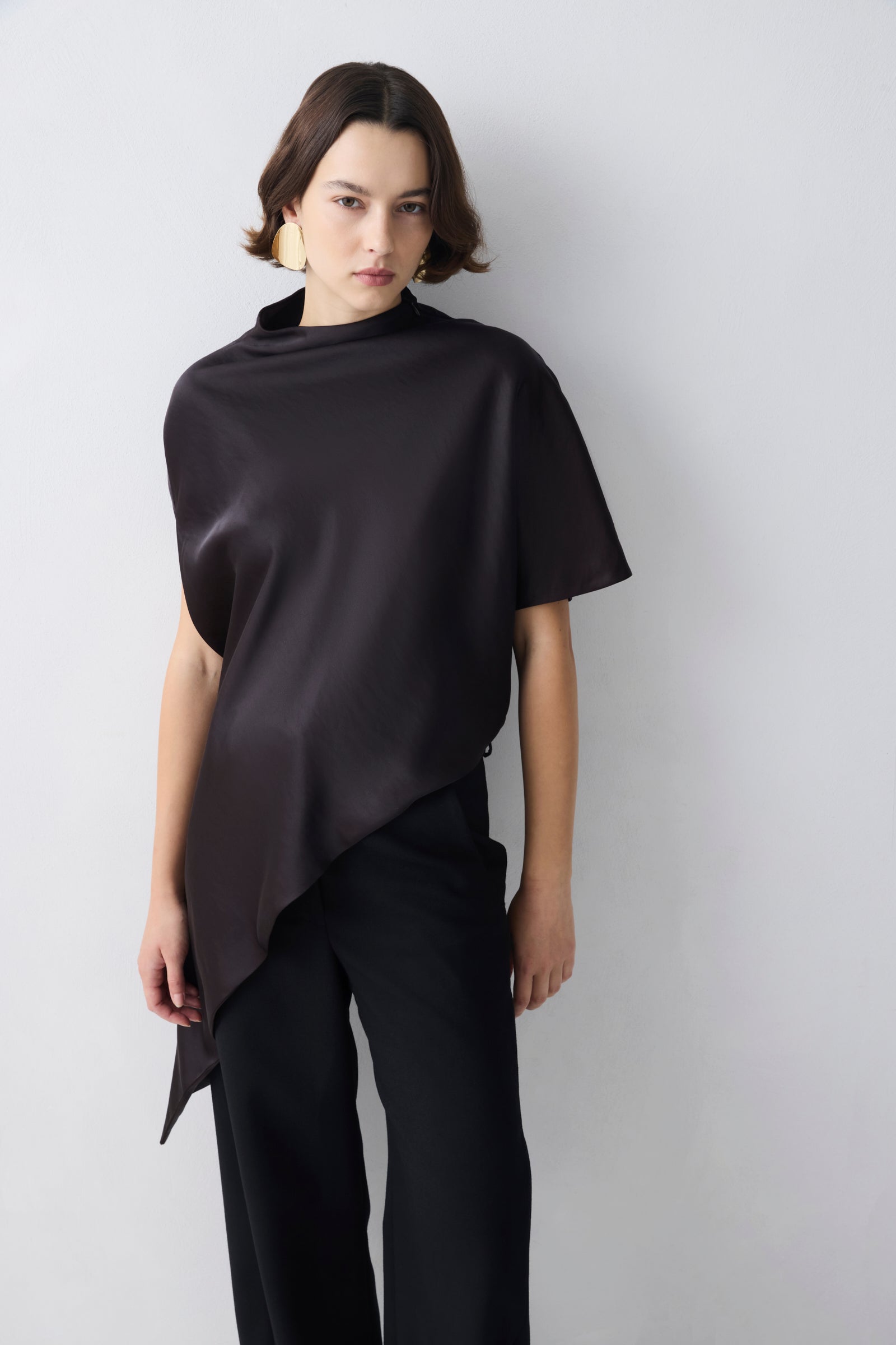 Person wearing a brown top over a black outfit on a white background