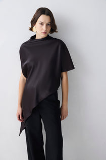 Person wearing a brown top over a black outfit on a white background