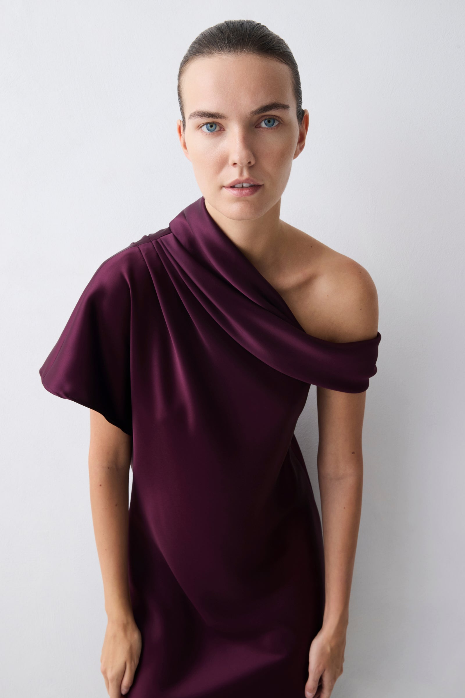 Woman wearing a purple off-shoulder dress against a white background