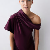 Woman wearing a purple off-shoulder dress against a white background
