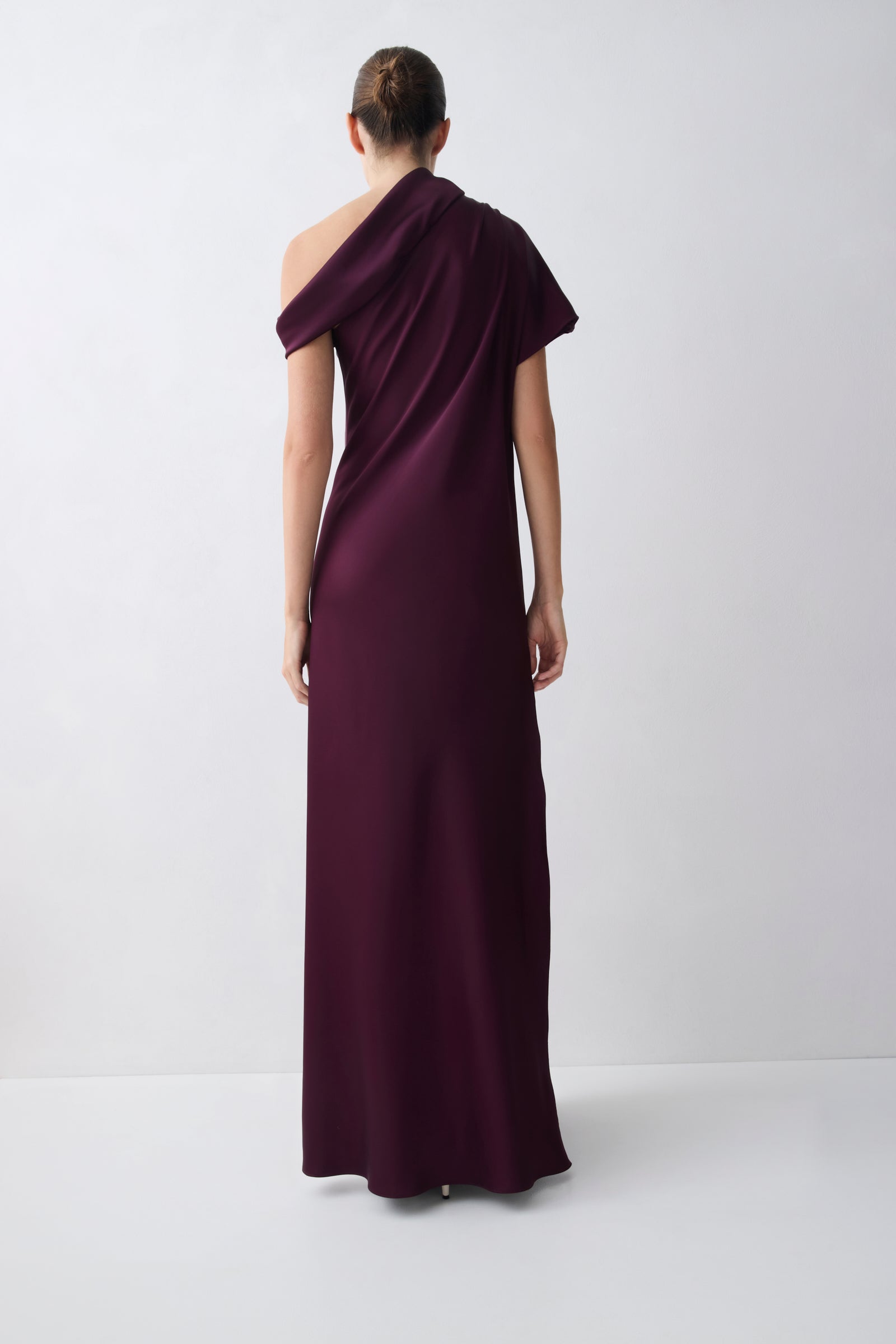 Woman wearing a one-shoulder purple gown on a white background