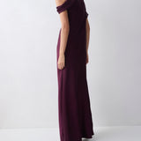 Woman wearing a long purple dress against a white background