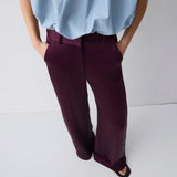 Person wearing a light blue shirt and dark purple pants on a white background