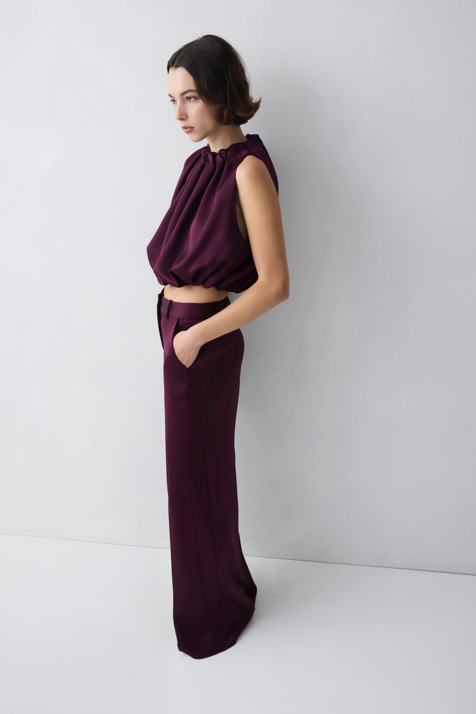 Woman wearing a dark purple outfit against a white background