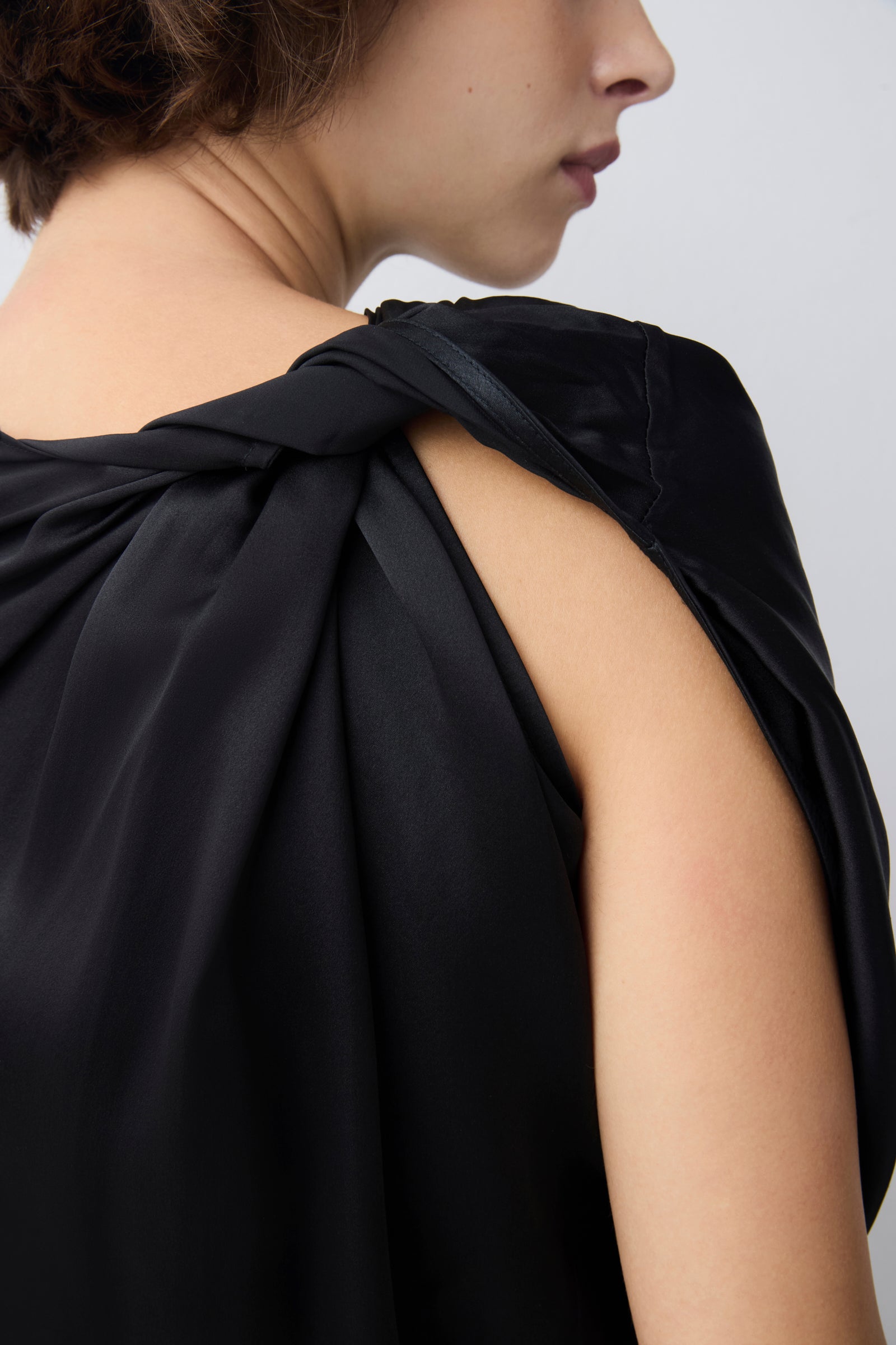 Black sleeveless top worn by a person on a plain background