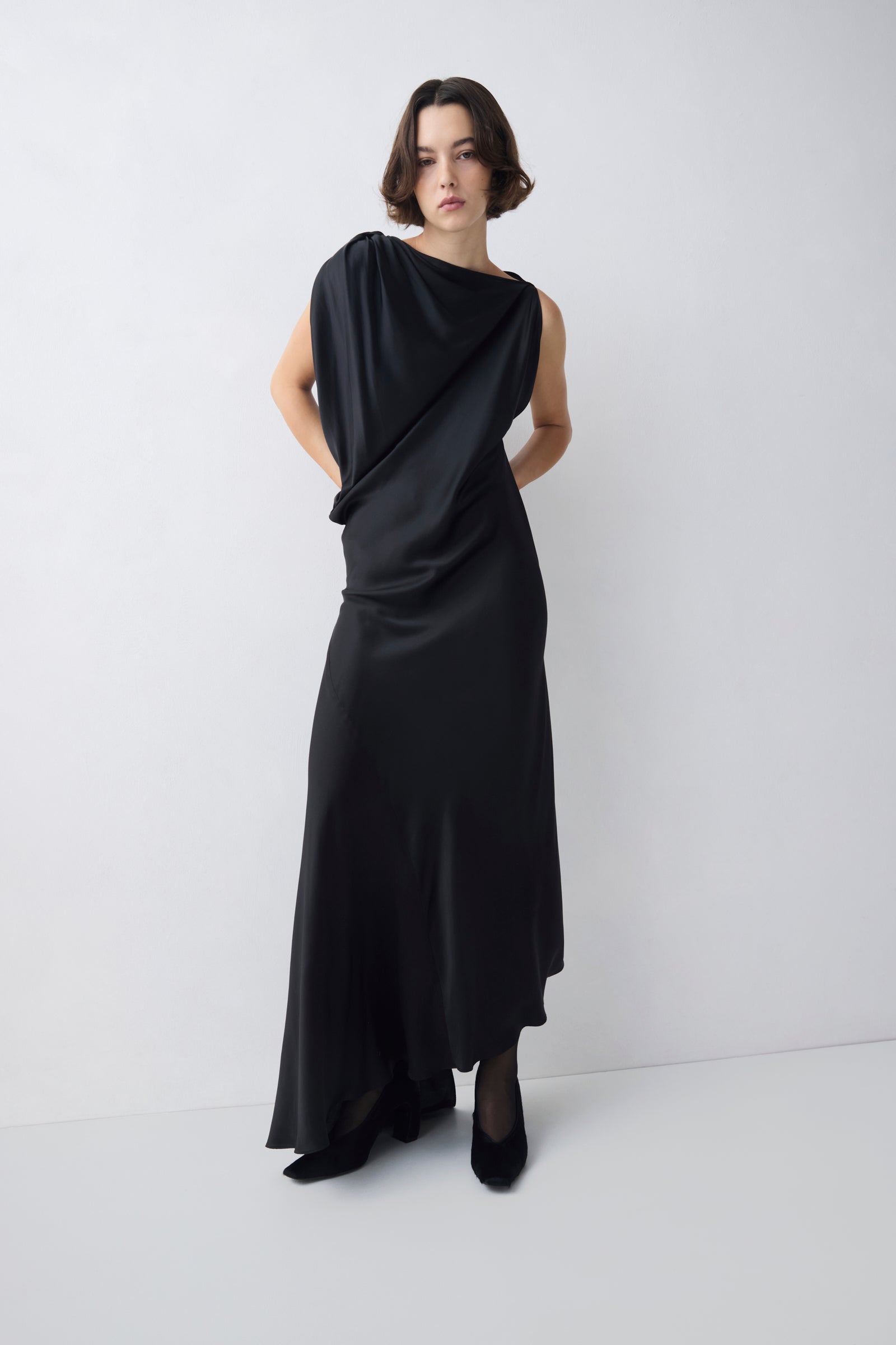 Woman wearing a black draped dress on a white background