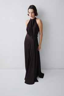 Woman wearing a brown halter neck gown against a white background