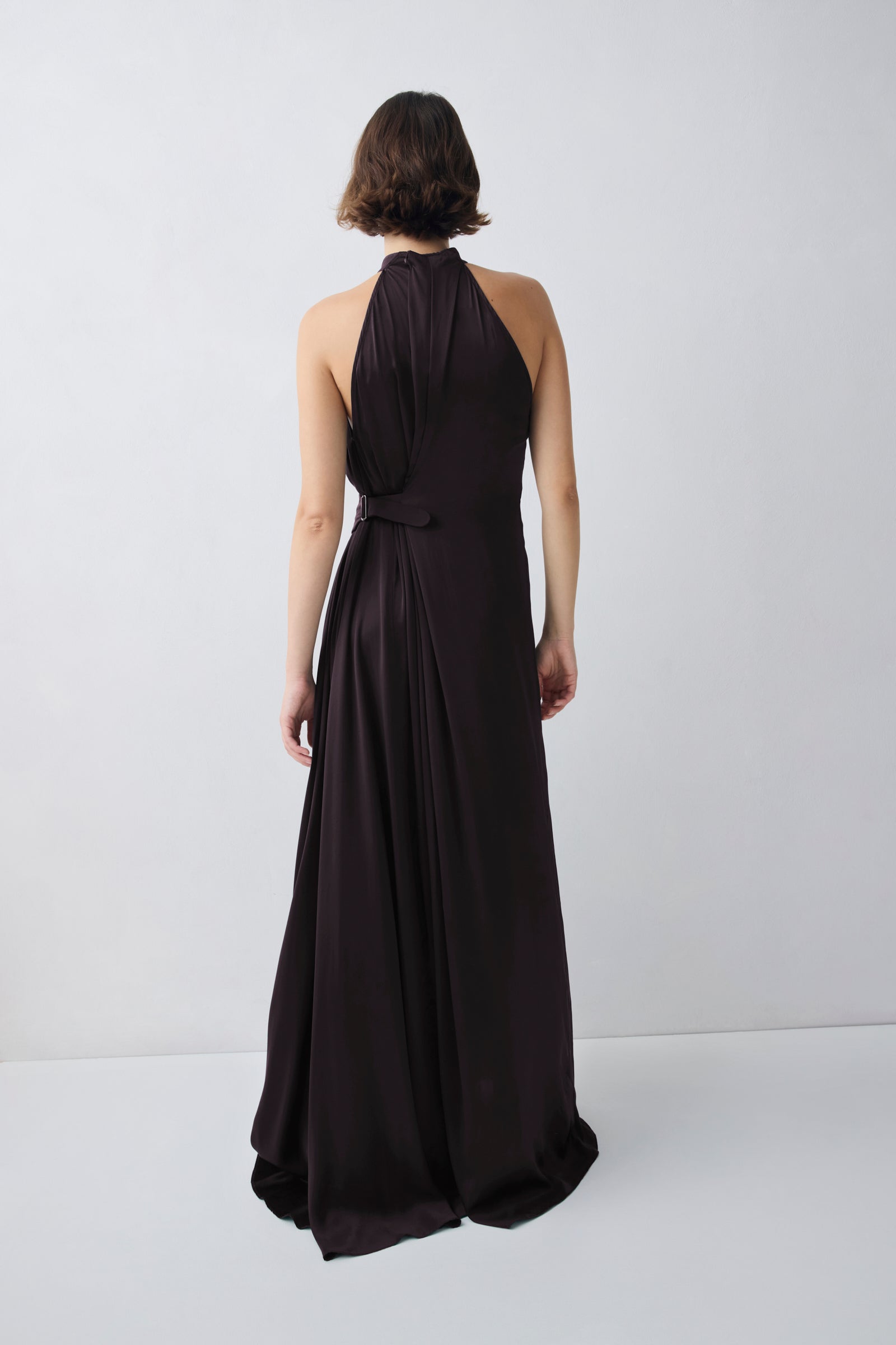 Woman wearing a black halter neck gown against a white background