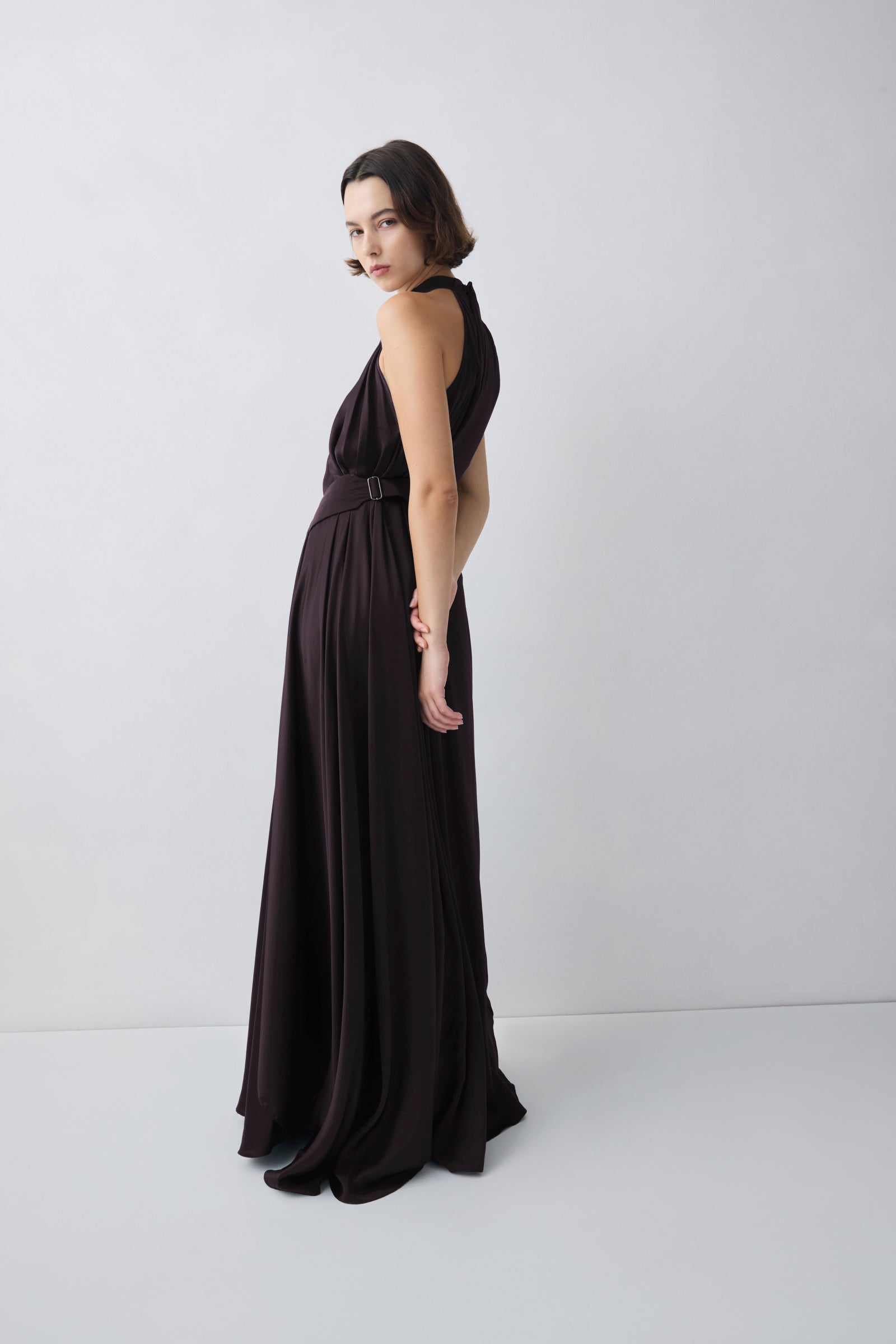 Woman wearing a dark green evening gown against a white background