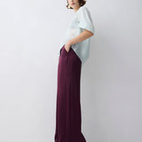 Woman wearing a white top and purple pants against a white background