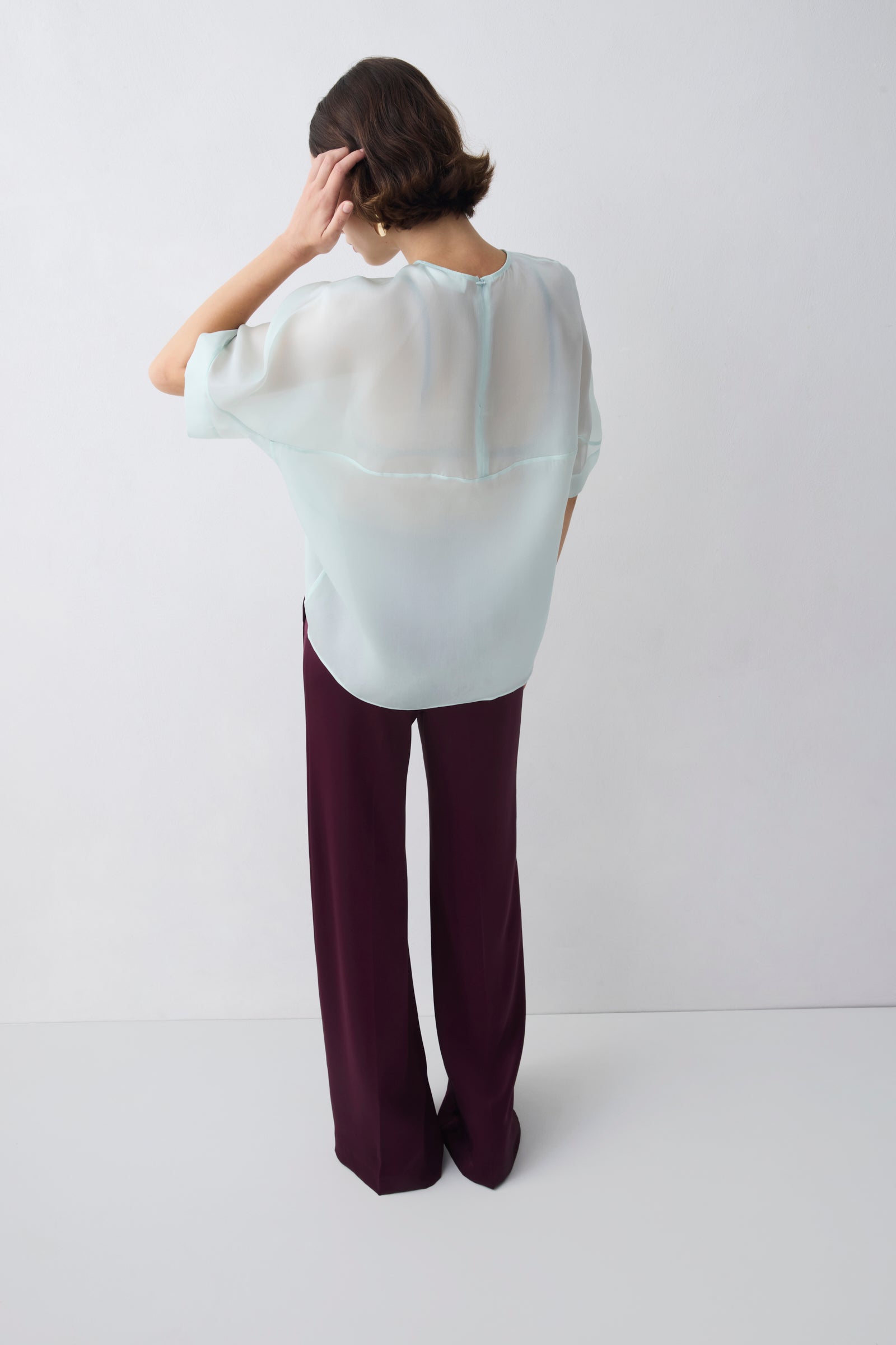Person wearing a white blouse and dark pants against a white background
