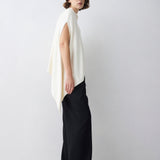 Woman wearing a white sleeveless top and black pants on a white background