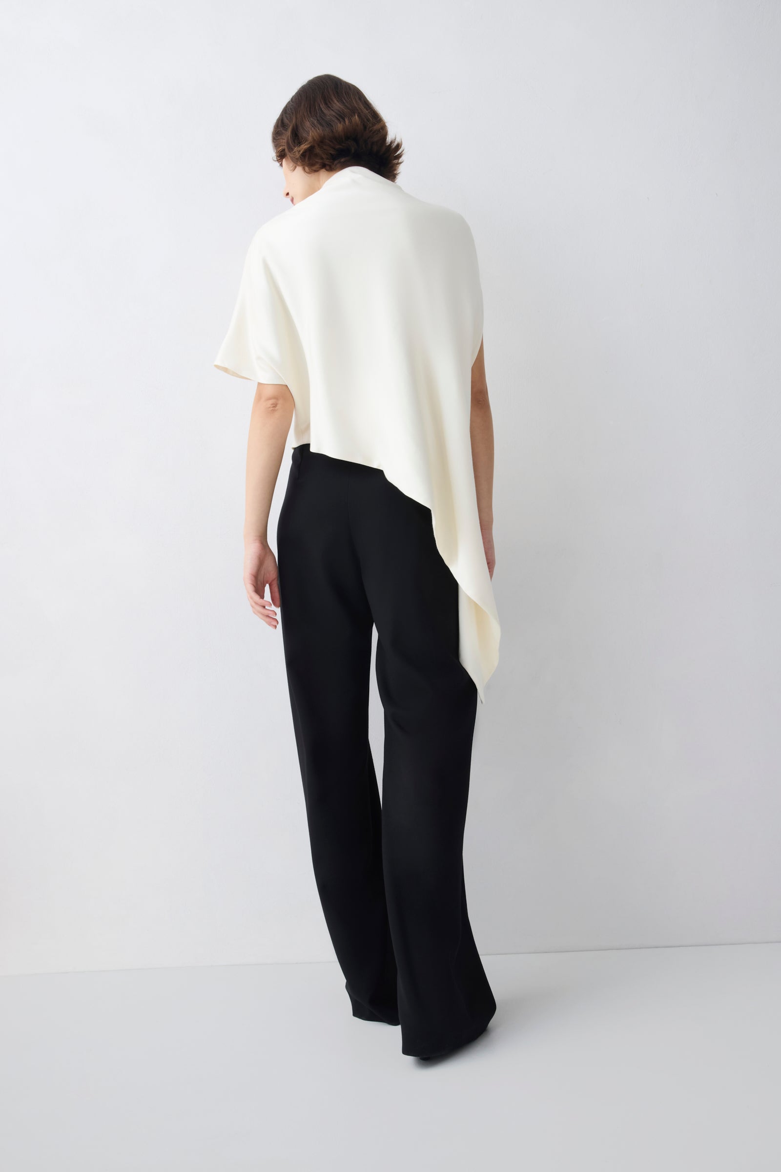 Person wearing a white top and black pants on a white background