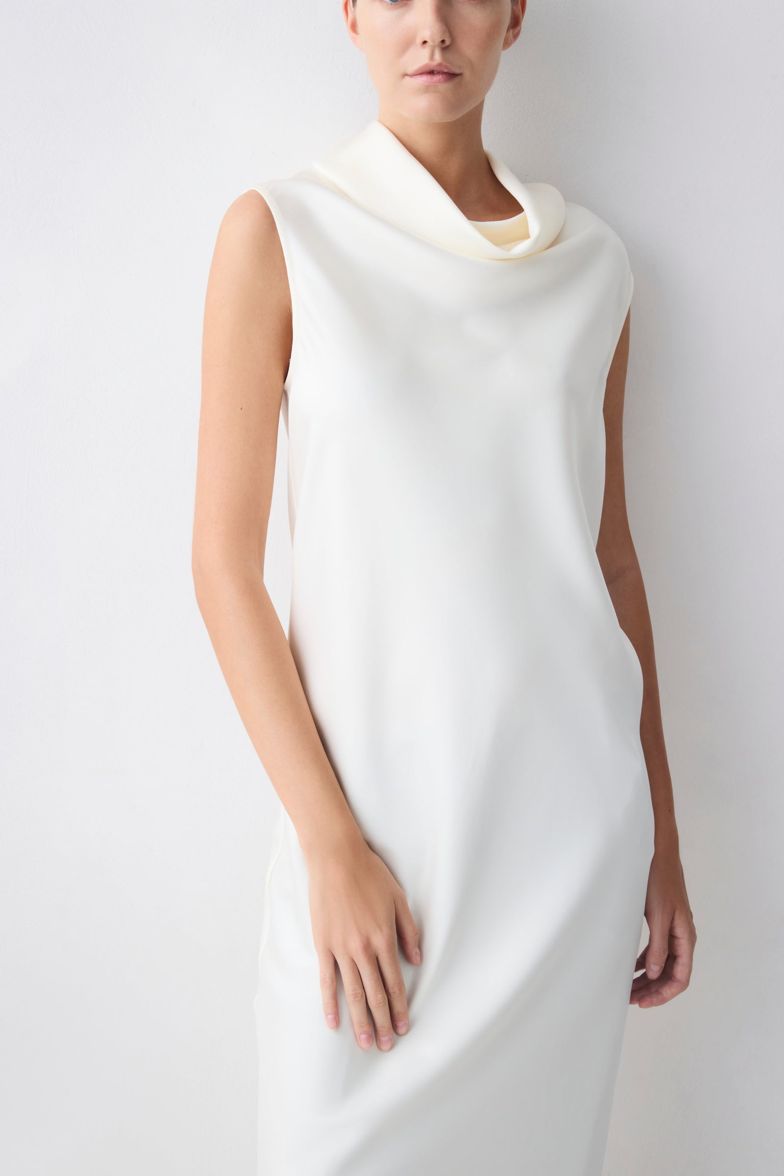 Woman wearing a white sleeveless dress against a plain background