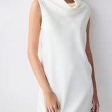 Woman wearing a white sleeveless dress against a plain background