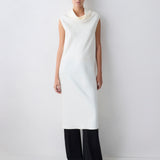 Person wearing a white sleeveless dress with a cowl neck against a plain background