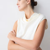 Woman wearing a white sleeveless top against a light gray background