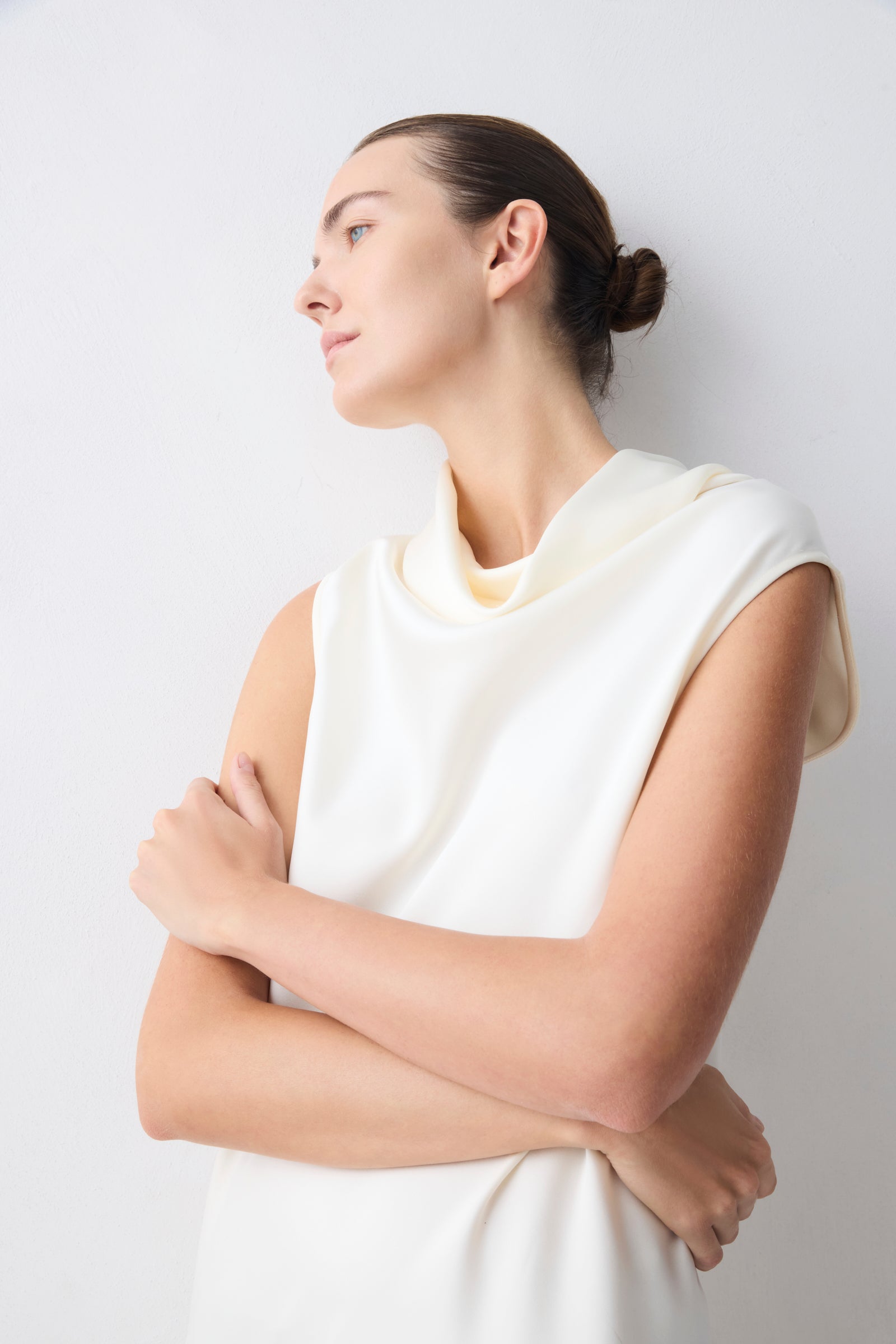 Woman wearing a white sleeveless top against a light gray background