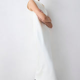 Person wearing a white sleeveless top and black pants against a plain background