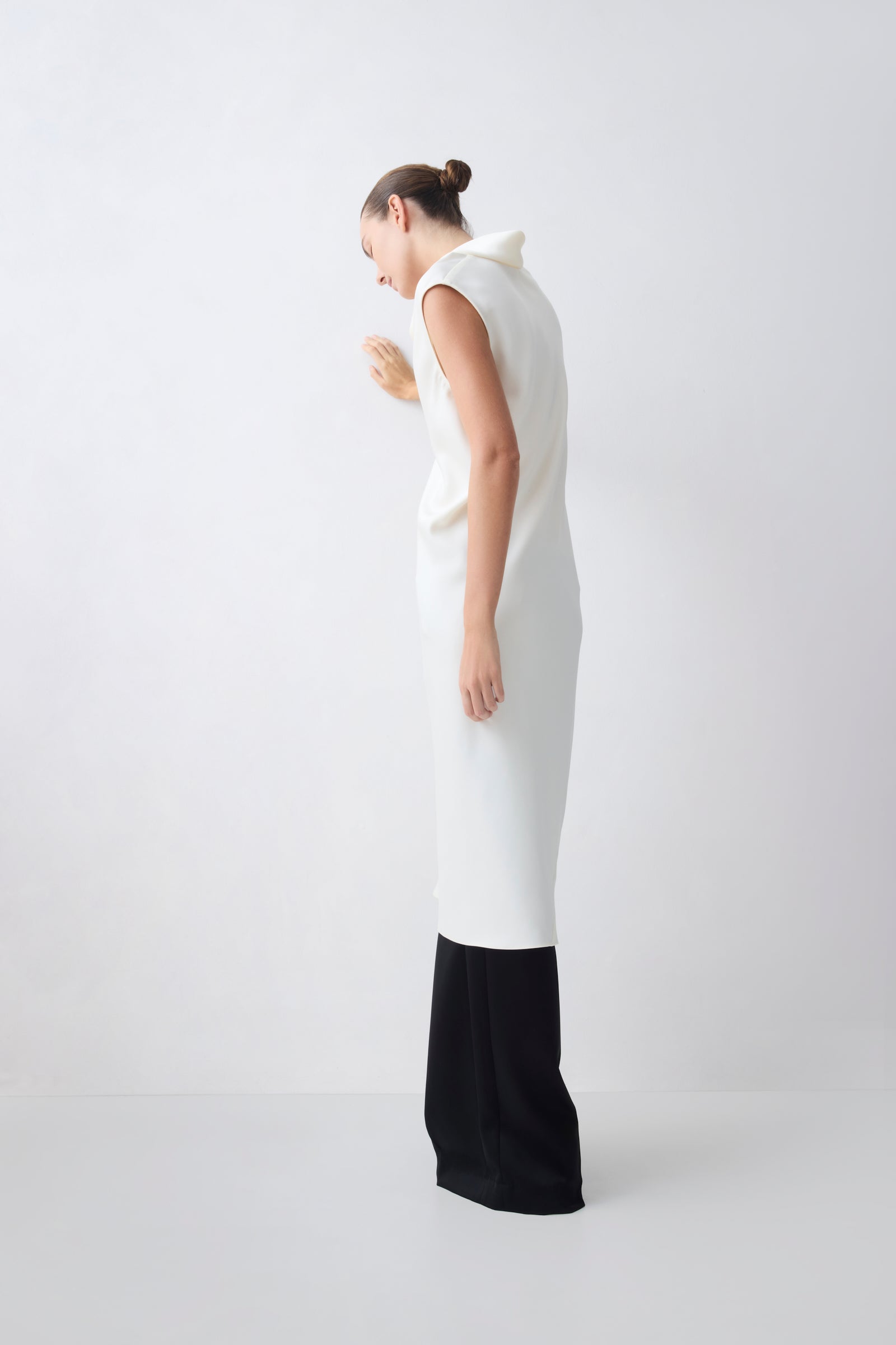 Woman wearing a white sleeveless top and black pants on a white background