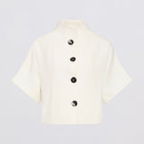 An off-white short-sleeve cropped jacket with a high stand collar and four black buttons down the front, displayed on a light gray background.