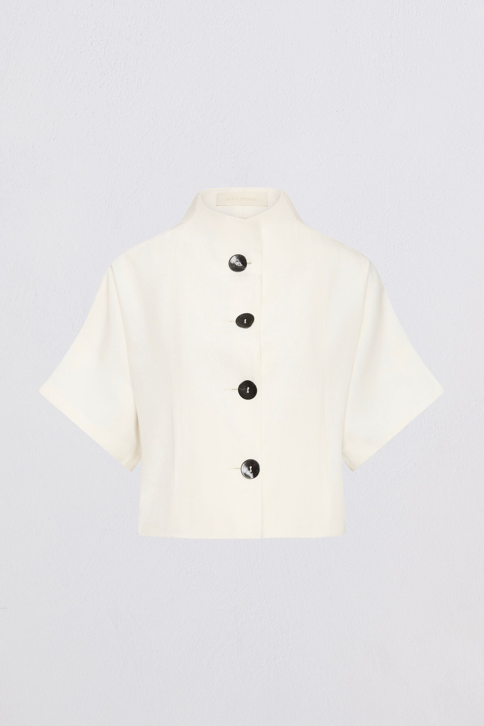 An off-white short-sleeve cropped jacket with a high stand collar and four black buttons down the front, displayed on a light gray background.