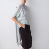 Woman wearing a light blue top and black pants against a white background