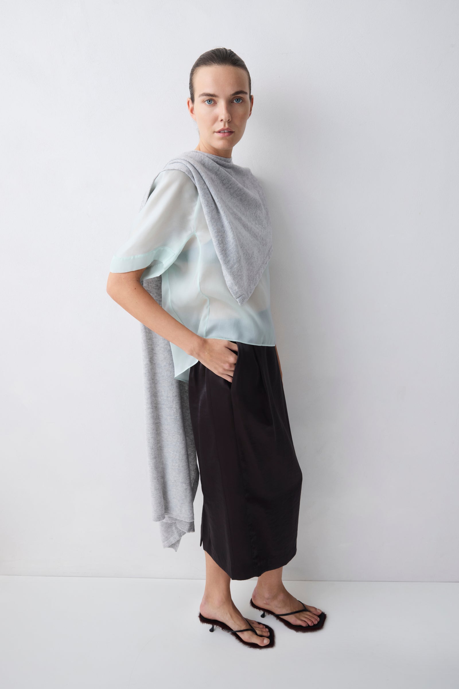 Woman wearing a light blue top and black pants against a white background