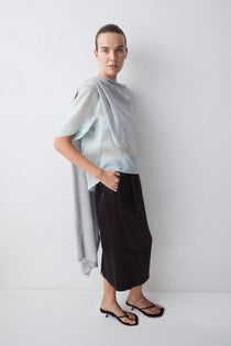 Woman wearing a light blue top and black pants against a white background