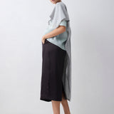 Woman wearing a light gray top and black skirt on a white background