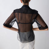 Woman wearing a black sheer top over a patterned dress on a white background