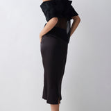 Person wearing a black dress with a unique back design on a white background