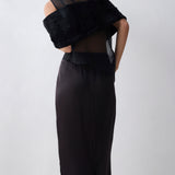 Person wearing a black dress with sheer overlay on a white background