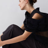 Woman wearing a black outfit sitting on a white background