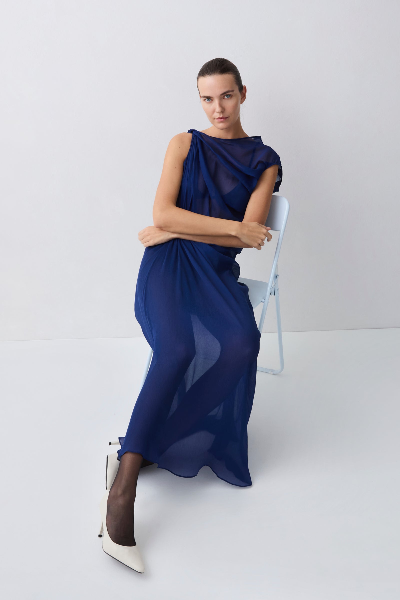 Woman wearing a blue dress standing against a white background