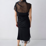 Person wearing a black dress with sheer back panels on a white background