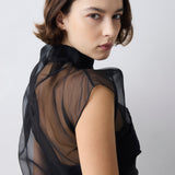 Woman wearing a black sheer blouse against a white background
