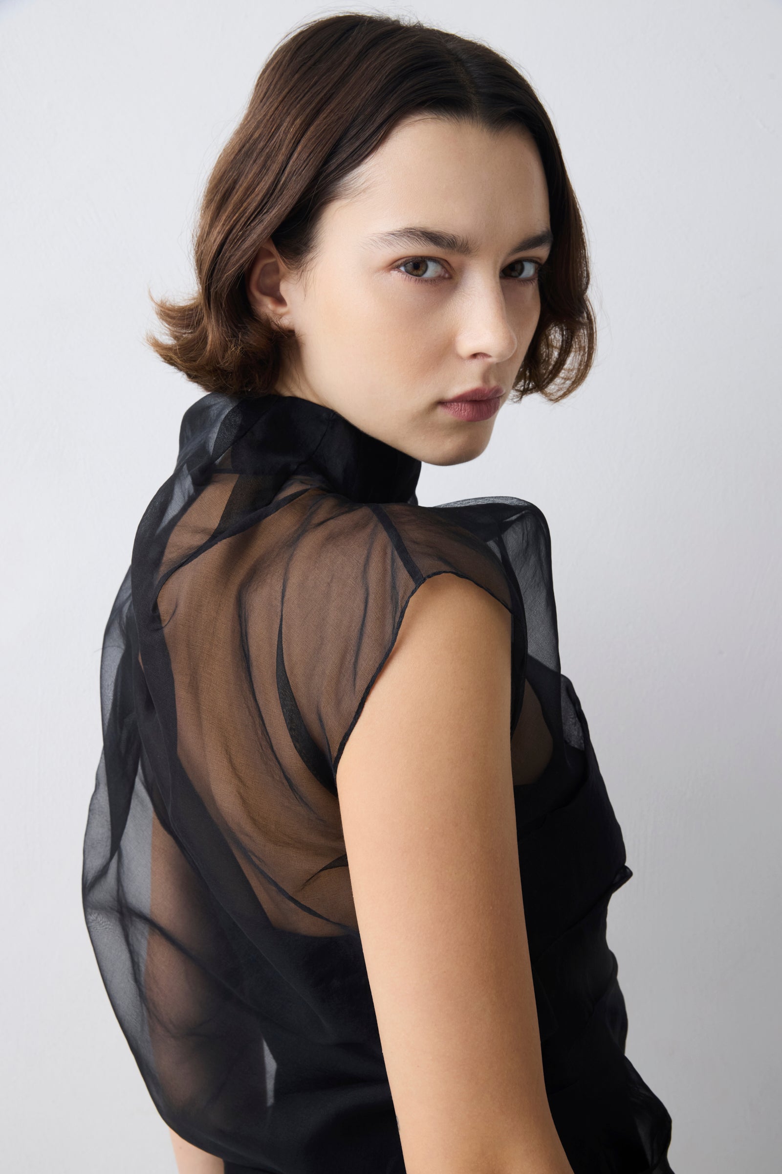 Woman wearing a black sheer blouse against a white background