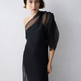 Woman wearing a black one-shoulder dress against a white background