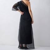 Woman wearing a black evening gown with sheer sleeves against a white background