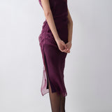 Woman wearing a purple dress with sheer overlay on a white background