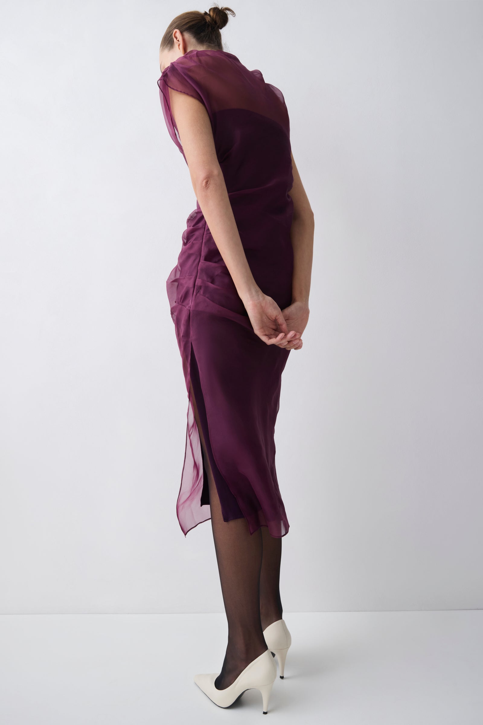 Woman wearing a purple dress with sheer overlay on a white background