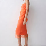 Woman wearing an orange dress standing against a white background