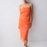 Woman wearing an orange strapless dress against a white background