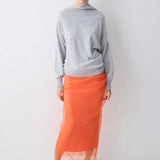 Person wearing a gray sweater and orange skirt on a white background