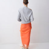 Person wearing a gray sweater and orange skirt on a white background