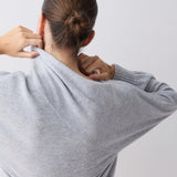 Person wearing a gray sweater against a white background