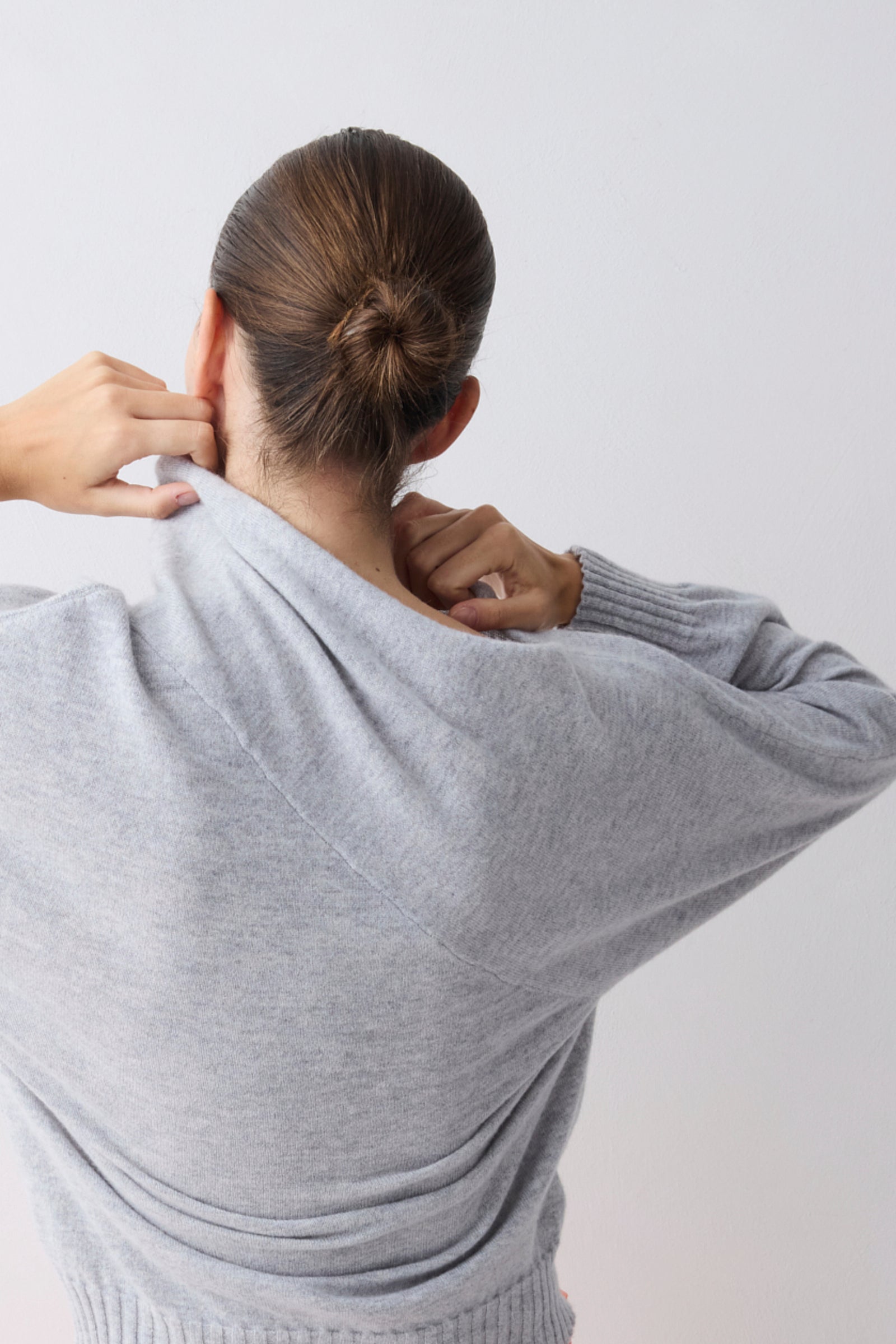 Person wearing a gray sweater against a white background